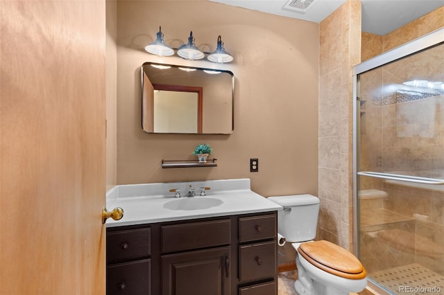 bathroom with vanity, toilet, and a shower with door