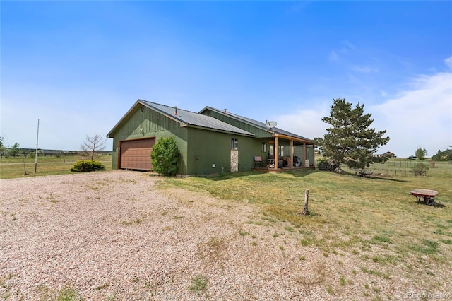 view of side of home featuring a rural view, a garage, and a lawn