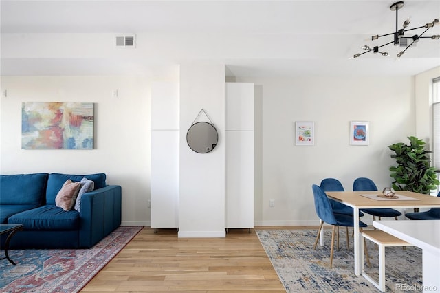 living room with light wood-style floors, visible vents, and baseboards