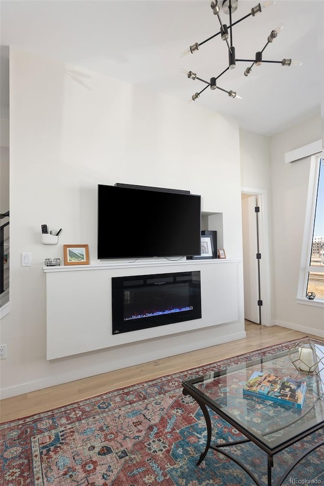 living area featuring a glass covered fireplace, baseboards, and wood finished floors