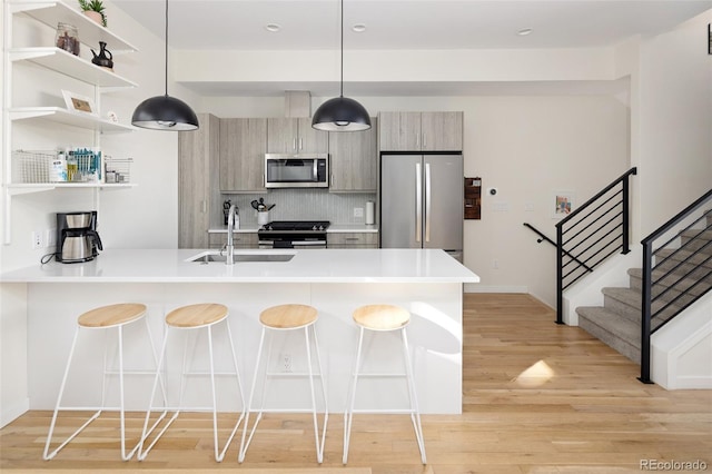 kitchen with light wood finished floors, a breakfast bar, a peninsula, stainless steel appliances, and a sink