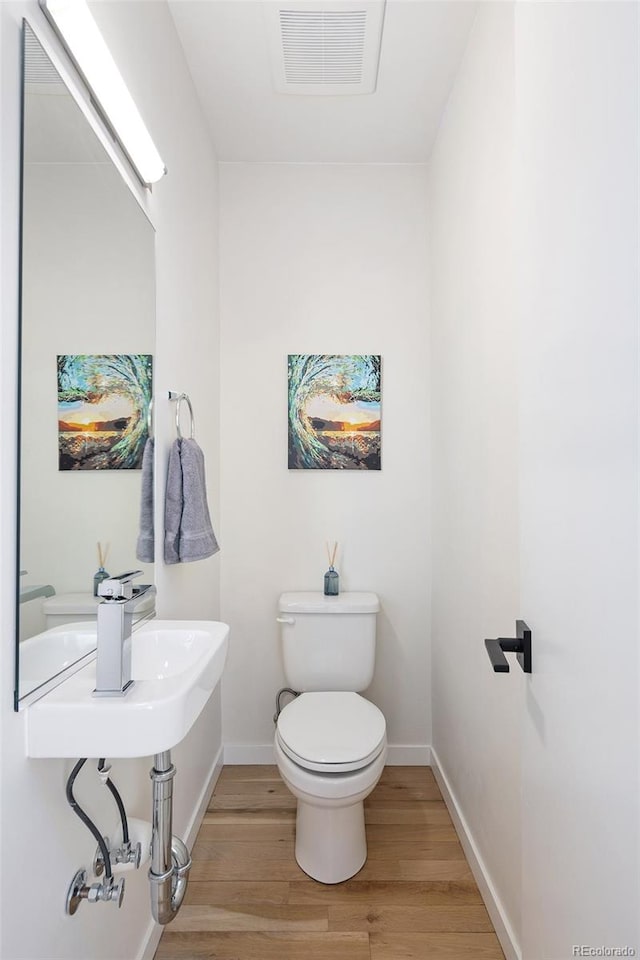 bathroom featuring toilet, baseboards, visible vents, and wood finished floors