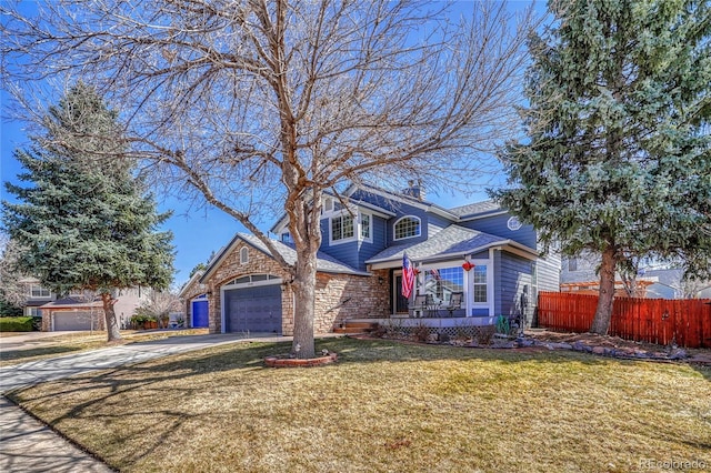 traditional-style home with an attached garage, a front lawn, fence, a chimney, and driveway