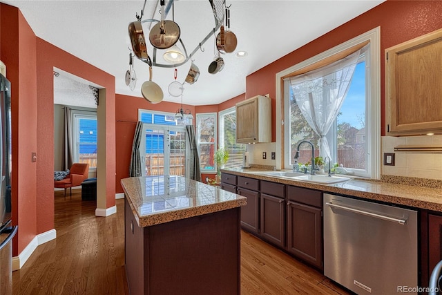 kitchen with a center island, tile countertops, dishwasher, wood finished floors, and a sink