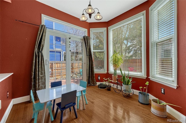 dining space featuring an inviting chandelier, wood finished floors, and baseboards