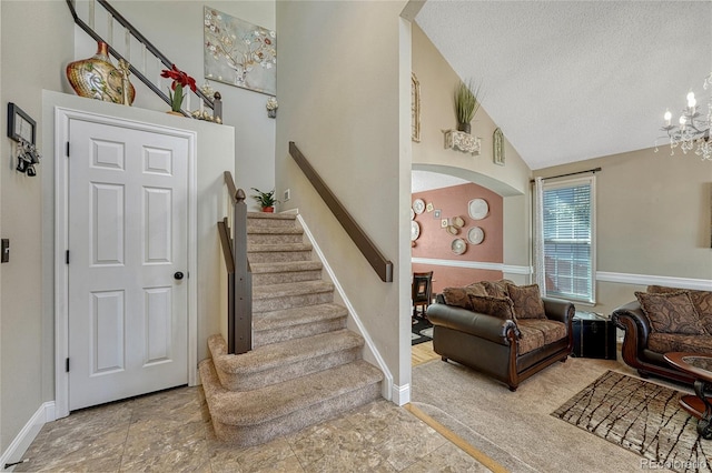 stairs with a notable chandelier, a textured ceiling, arched walkways, baseboards, and vaulted ceiling