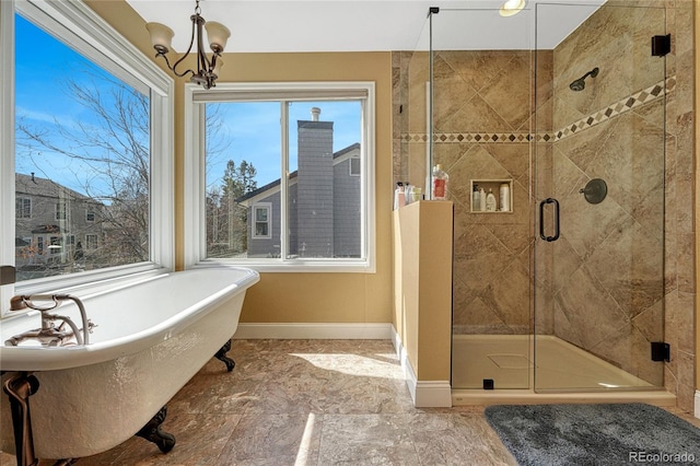 bathroom with a chandelier, a shower stall, baseboards, and a freestanding tub