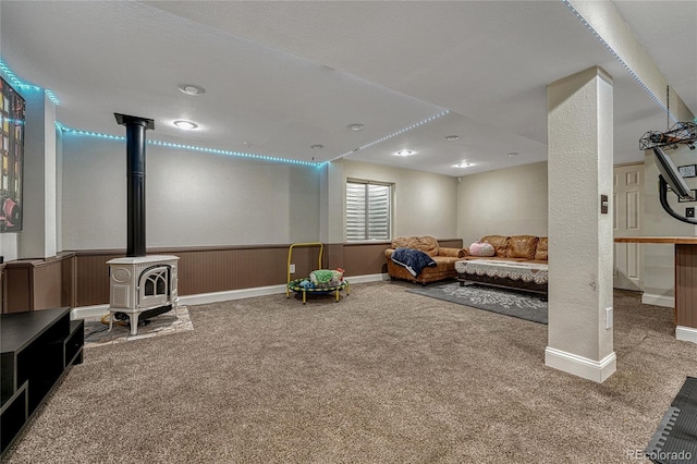 interior space featuring a wainscoted wall, a wood stove, and carpet floors