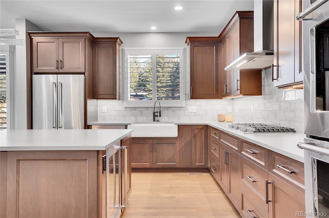 kitchen featuring sink, stainless steel appliances, beverage cooler, decorative backsplash, and wall chimney range hood