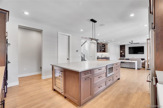 kitchen featuring tasteful backsplash, light hardwood / wood-style floors, a kitchen island, decorative light fixtures, and beverage cooler