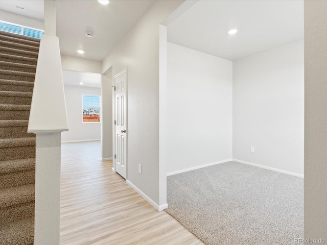 hallway featuring stairs, baseboards, and recessed lighting