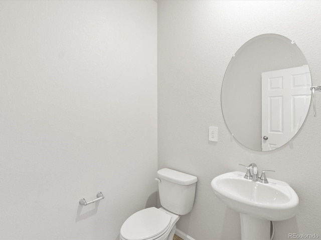 bathroom with baseboards, a sink, and toilet