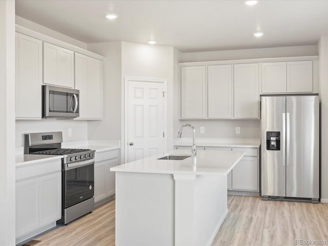 kitchen with light wood finished floors, stainless steel appliances, recessed lighting, light countertops, and a sink