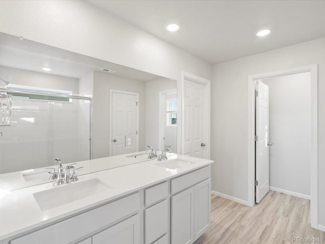 full bath with double vanity, wood finished floors, a stall shower, and a sink