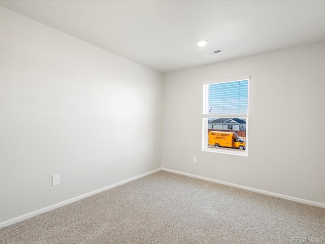 spare room with carpet floors, visible vents, and baseboards