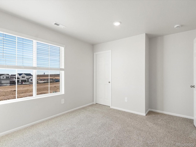 carpeted spare room with visible vents and baseboards