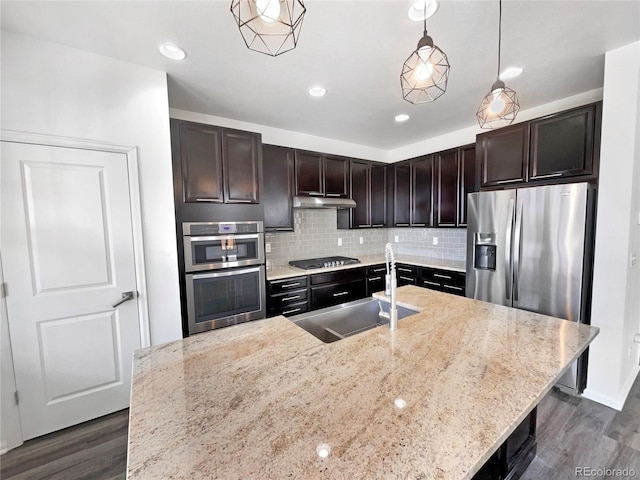 kitchen featuring dark wood-style floors, a sink, under cabinet range hood, appliances with stainless steel finishes, and tasteful backsplash