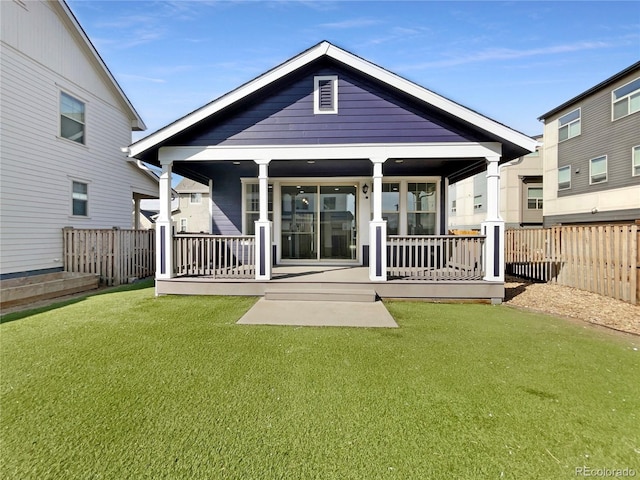 rear view of house with a lawn, a porch, and fence
