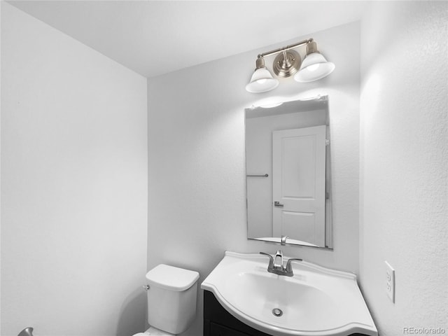 half bathroom featuring vanity and toilet