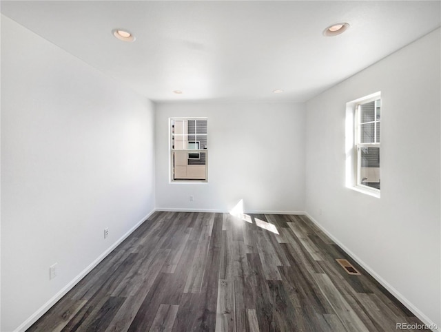 unfurnished room featuring dark wood-type flooring, recessed lighting, and baseboards