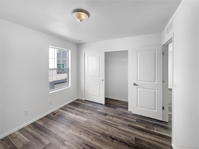 unfurnished bedroom featuring visible vents, baseboards, a closet, and dark wood finished floors