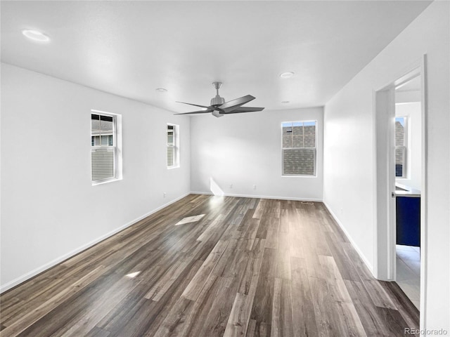 spare room featuring a ceiling fan, plenty of natural light, wood finished floors, and baseboards