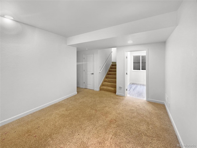 carpeted empty room with stairway and baseboards