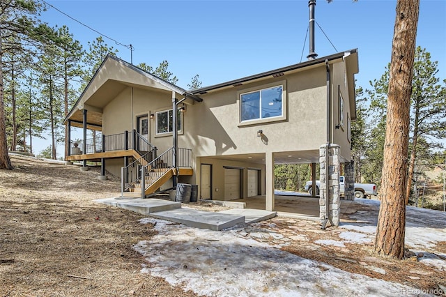 rear view of house with stairway, a garage, and stucco siding