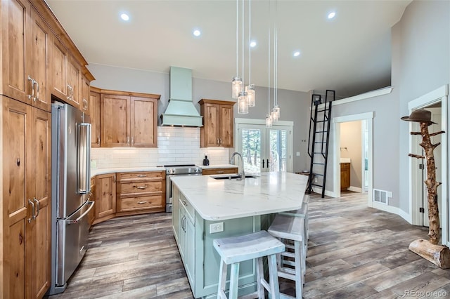 kitchen with custom range hood, a sink, backsplash, dark wood-style floors, and stainless steel appliances