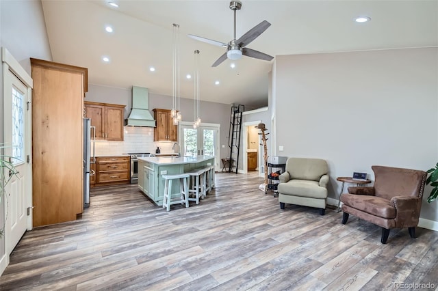 kitchen with premium range hood, an island with sink, stainless steel appliances, light countertops, and open floor plan