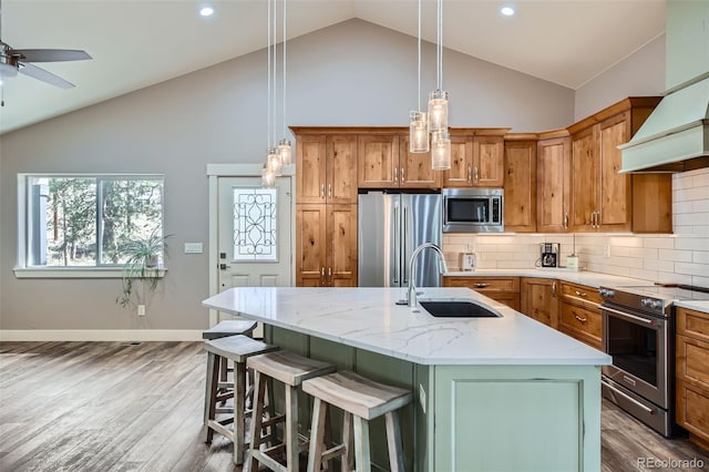 kitchen with decorative backsplash, brown cabinets, appliances with stainless steel finishes, wood finished floors, and a sink