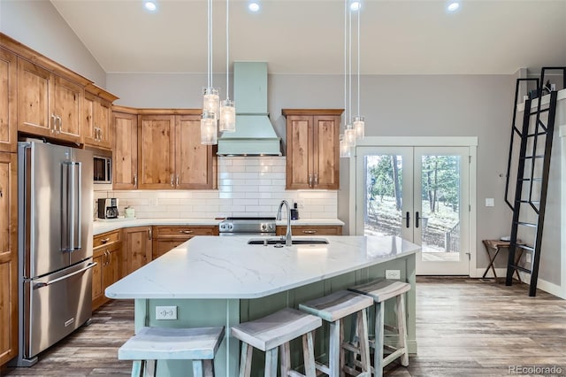 kitchen featuring premium range hood, a kitchen bar, decorative backsplash, appliances with stainless steel finishes, and a sink