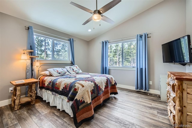 bedroom featuring vaulted ceiling, multiple windows, and wood finished floors