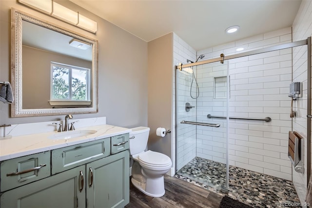 full bath with a stall shower, toilet, vanity, and wood finished floors