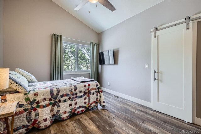 bedroom with a ceiling fan, wood finished floors, a barn door, baseboards, and lofted ceiling