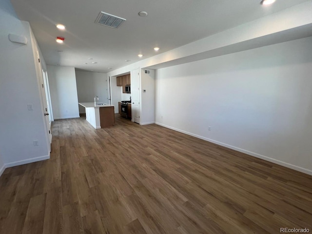 6648 N Nepal Ct, Aurora, CO 80019 - unfurnished living room with dark wood-style flooring, recessed lighting, baseboards, and a sink