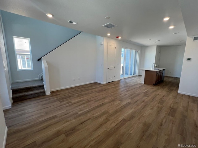 6648 N Nepal Ct, Aurora, CO 80019 - unfurnished living room with healthy amount of natural light, baseboards, stairway, dark wood-style floors, and recessed lighting