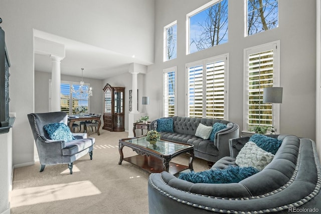 living room featuring ornate columns, a chandelier, a wealth of natural light, and carpet flooring