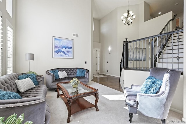 living area featuring baseboards, visible vents, stairway, an inviting chandelier, and a high ceiling