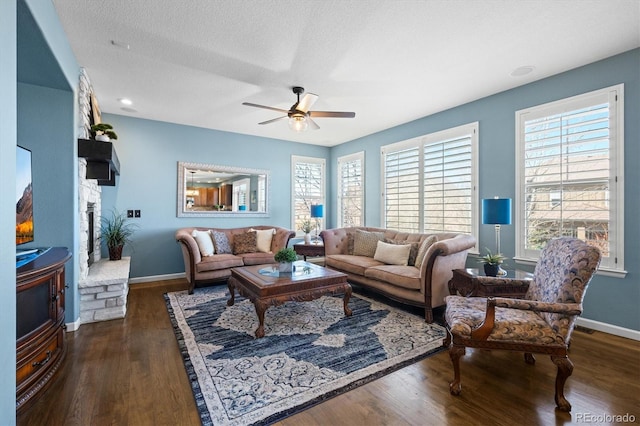 living room featuring dark wood-type flooring, a textured ceiling, baseboards, and a ceiling fan