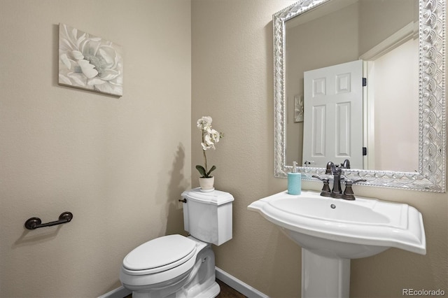 half bath featuring toilet and baseboards