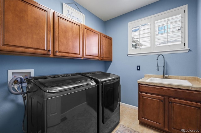 washroom featuring washing machine and dryer, cabinet space, a sink, and baseboards