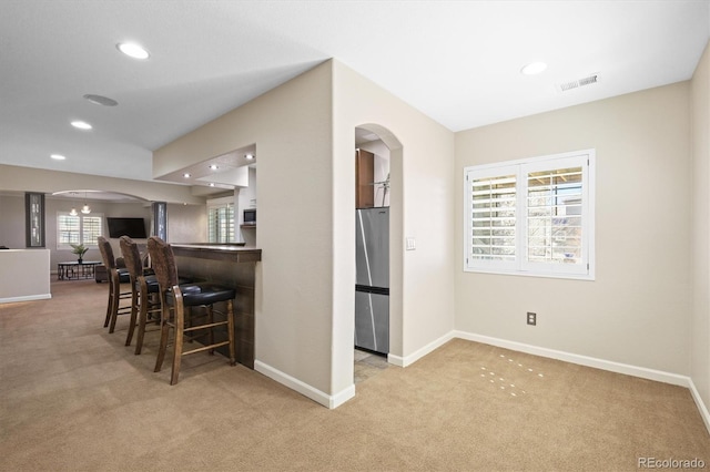 bar featuring arched walkways, carpet, stainless steel appliances, a wealth of natural light, and baseboards