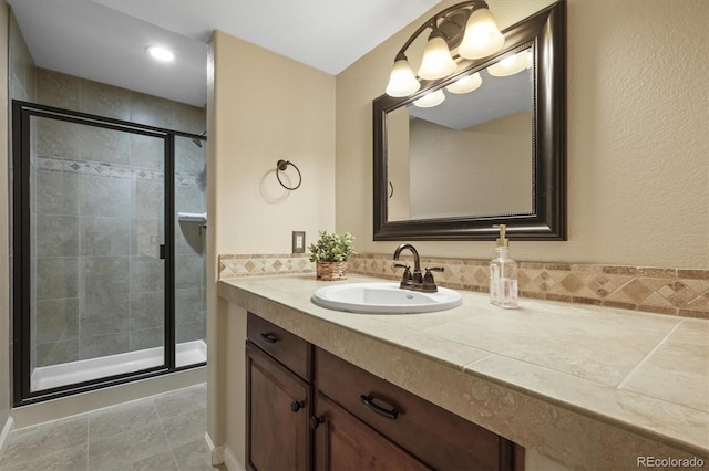 full bath featuring a shower stall, vanity, and tile patterned floors