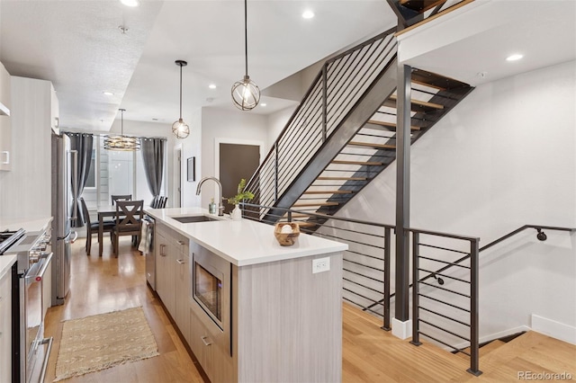 1836 Grove St Unit 108, Denver, CO 80204 - kitchen with a sink, appliances with stainless steel finishes, a kitchen island with sink, light wood-type flooring, and recessed lighting