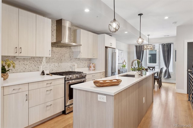 1836 Grove St Unit 108, Denver, CO 80204 - kitchen with appliances with stainless steel finishes, wall chimney range hood, a center island with sink, light wood finished floors, and light countertops