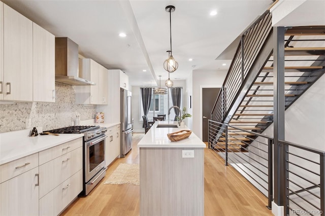1836 Grove St Unit 108, Denver, CO 80204 - kitchen with wall chimney exhaust hood, appliances with stainless steel finishes, an island with sink, a sink, and decorative backsplash