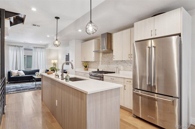 1836 Grove St Unit 108, Denver, CO 80204 - kitchen with high end appliances, wall chimney exhaust hood, a sink, light wood-type flooring, and light countertops