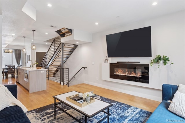 1836 Grove St Unit 108, Denver, CO 80204 - living room featuring light wood-type flooring, a glass covered fireplace, recessed lighting, stairs, and baseboards