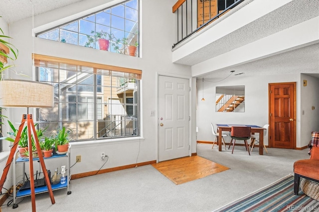 carpeted entryway featuring a textured ceiling and a high ceiling